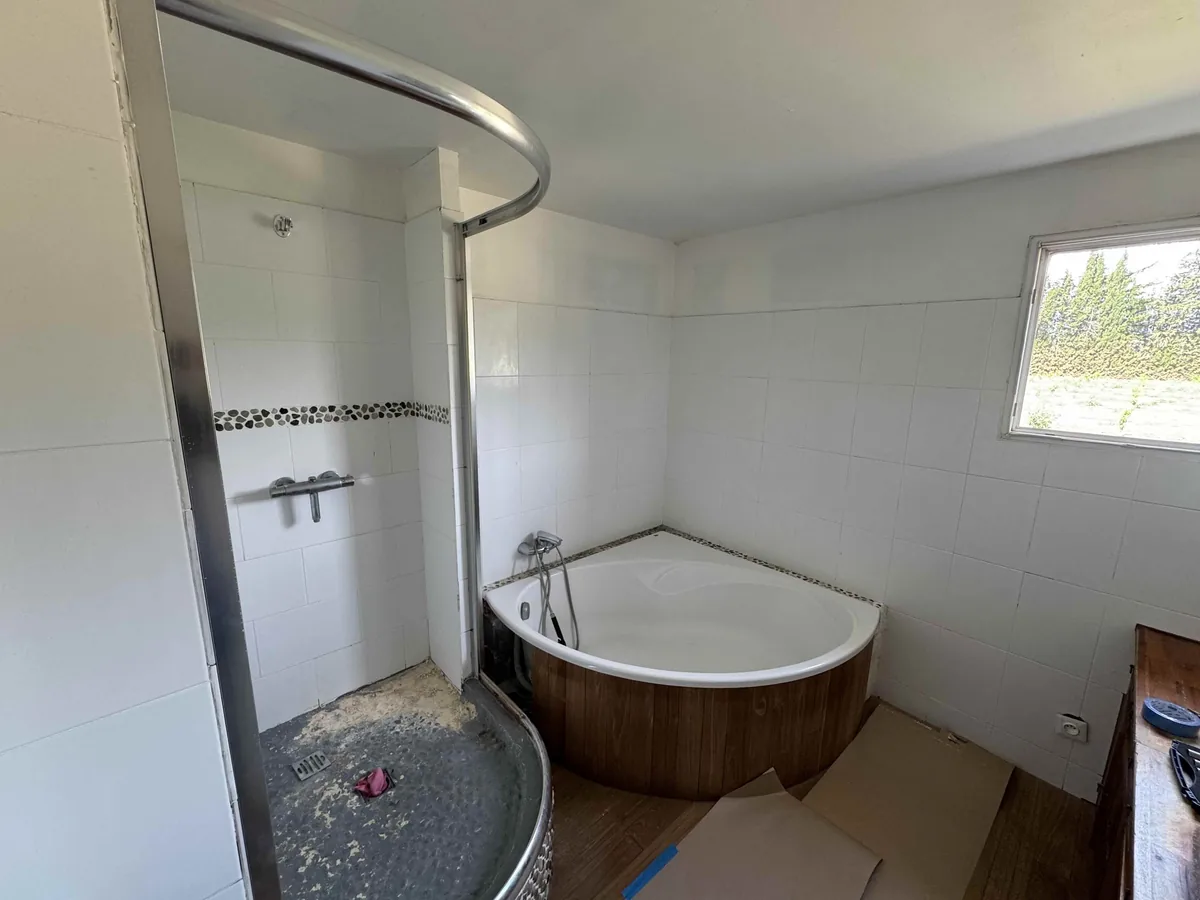 Salle de bains avant travaux : baignoire d'angle en bois et cabine de douche à receveur surélevé